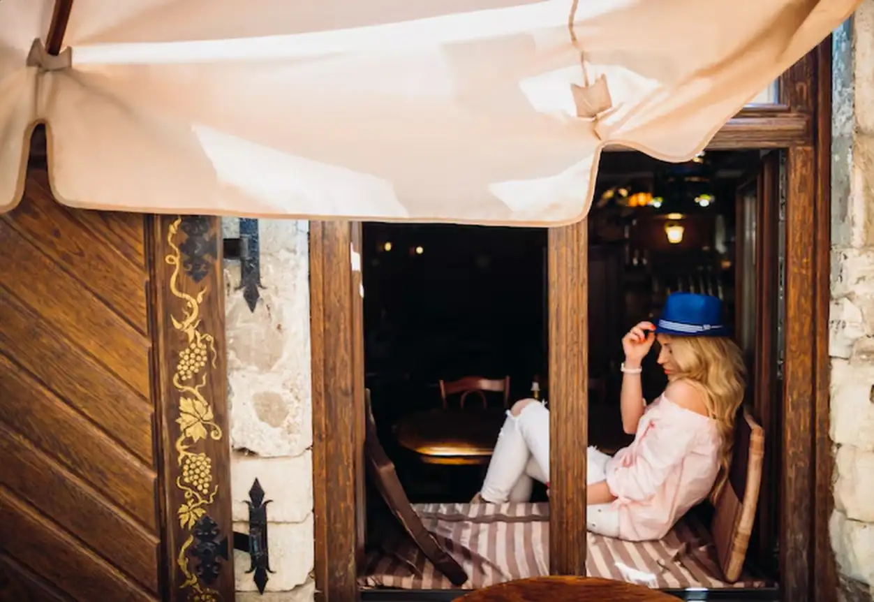 Woman in blue hat sits on the windowsill in the cafe