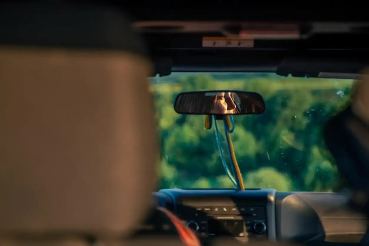 A young woman driving a red suv in the countryside face reflection