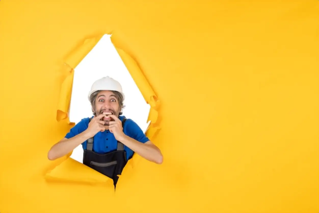 Front view male builder in uniform on the yellow background